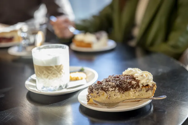 Latte macchiato with a slice of Limburg vlaai and whipped cream
